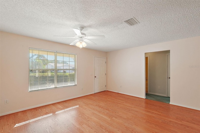 empty room featuring light hardwood / wood-style floors, ceiling fan, and a textured ceiling