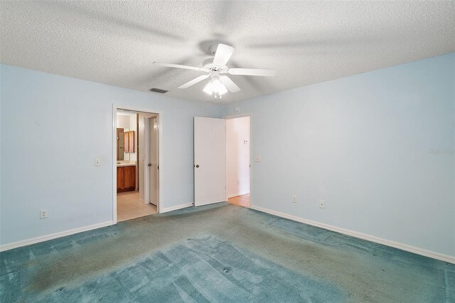 unfurnished bedroom featuring a textured ceiling, light carpet, ceiling fan, and ensuite bathroom