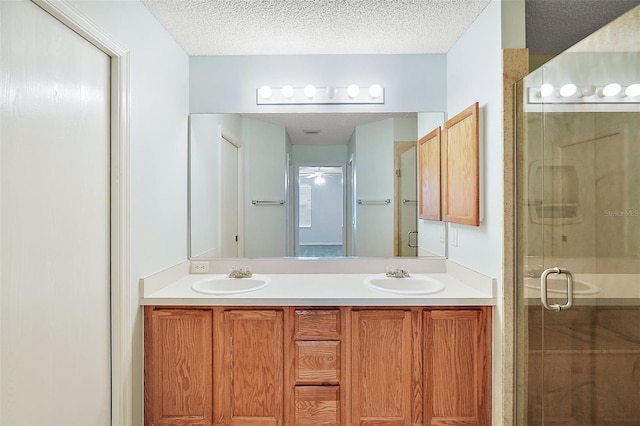 bathroom featuring a textured ceiling, vanity, ceiling fan, and an enclosed shower