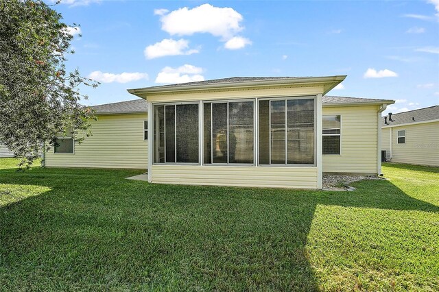 rear view of house featuring a sunroom and a yard