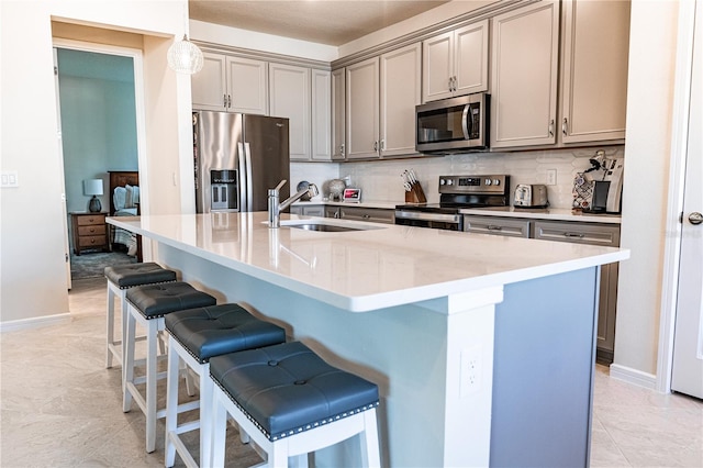 kitchen featuring pendant lighting, sink, a center island with sink, backsplash, and appliances with stainless steel finishes