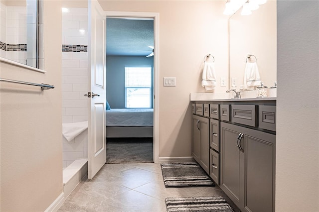 bathroom featuring a textured ceiling, a tile shower, tile patterned flooring, and vanity