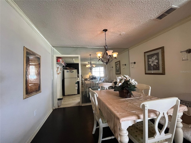 dining area with a notable chandelier, a textured ceiling, ornamental molding, and hardwood / wood-style flooring