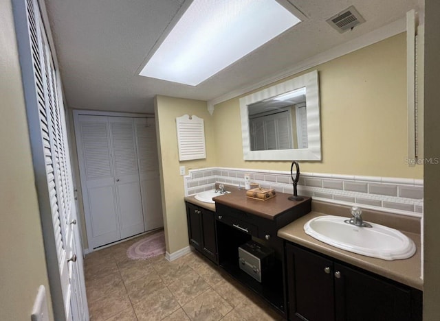 bathroom with vanity, a textured ceiling, tasteful backsplash, and tile patterned floors