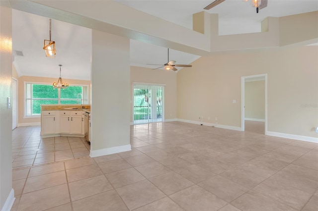 empty room featuring ceiling fan with notable chandelier, high vaulted ceiling, and light tile patterned flooring