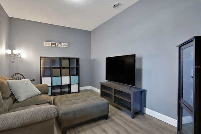 living room featuring high vaulted ceiling, wood-type flooring, and a textured ceiling