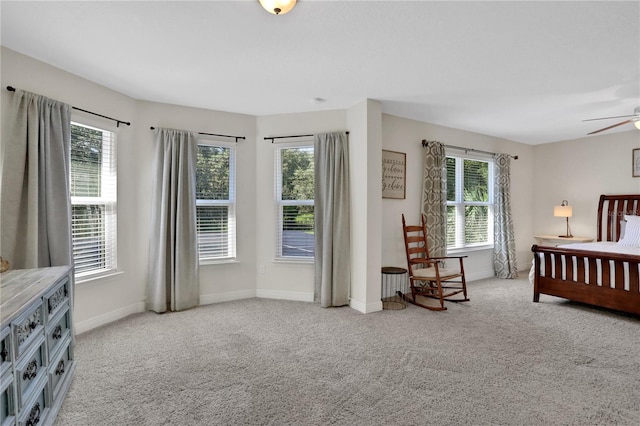 bedroom featuring ceiling fan, light carpet, and multiple windows