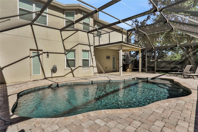 view of pool featuring a patio, glass enclosure, and ceiling fan