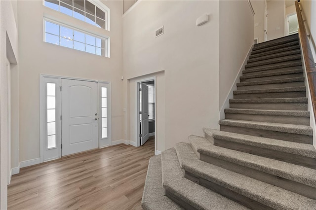 entrance foyer with visible vents, stairs, light wood-style flooring, and baseboards