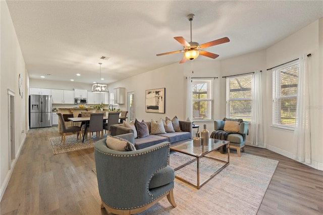 living room featuring light wood finished floors, baseboards, visible vents, ceiling fan, and recessed lighting