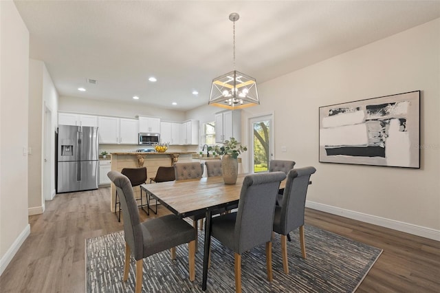 dining room with light wood-type flooring, a notable chandelier, baseboards, and recessed lighting