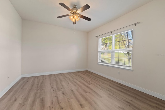 unfurnished room with a ceiling fan, light wood finished floors, and baseboards