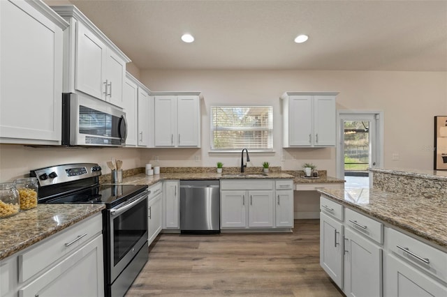 kitchen featuring light wood-style flooring, recessed lighting, a sink, white cabinets, and appliances with stainless steel finishes