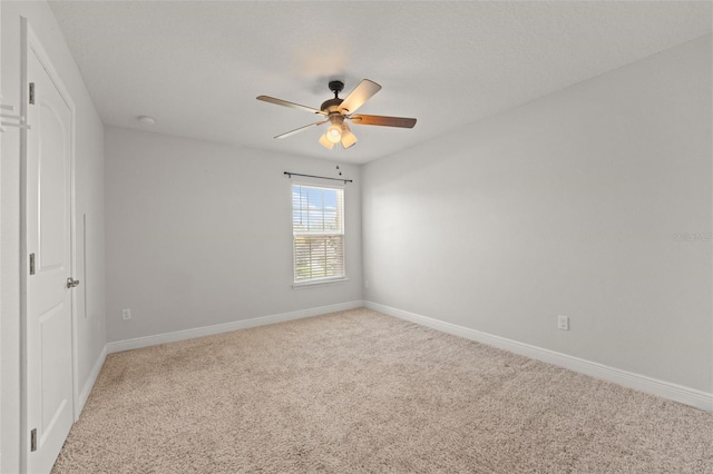 spare room with ceiling fan, baseboards, and light colored carpet