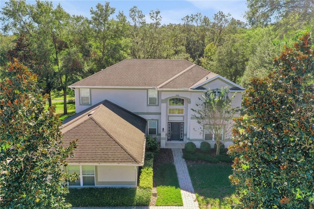 traditional home featuring a shingled roof and stucco siding