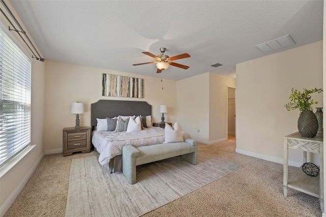 bedroom featuring a ceiling fan, visible vents, light carpet, and baseboards