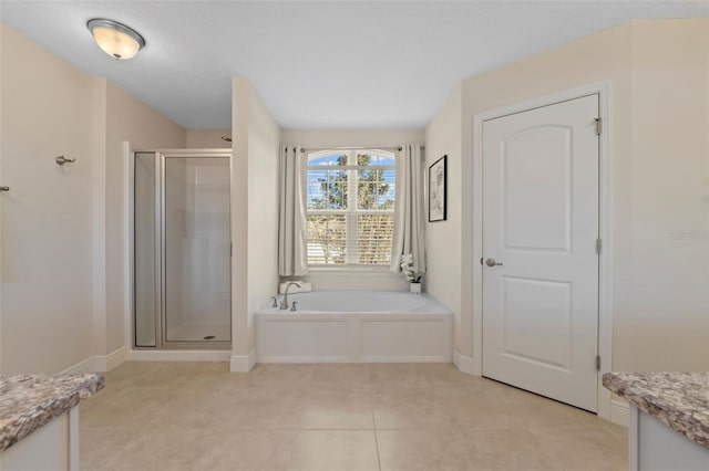 bathroom with a garden tub, vanity, a shower stall, baseboards, and tile patterned floors