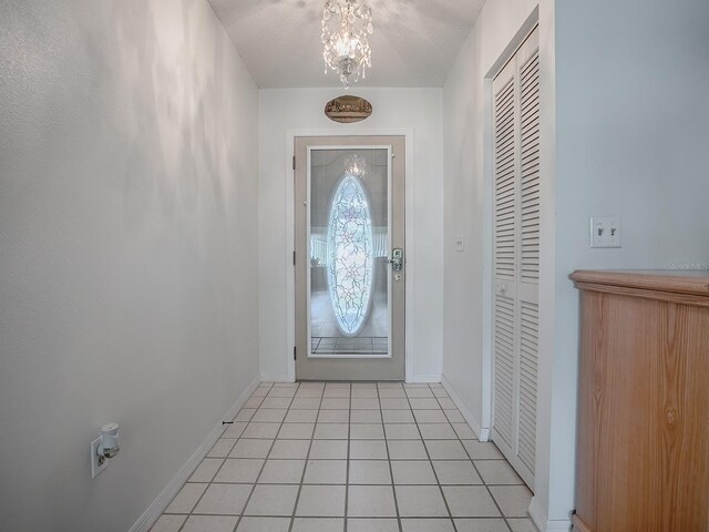 tiled foyer entrance with a chandelier and a textured ceiling