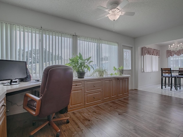 office space with ceiling fan with notable chandelier, light hardwood / wood-style floors, plenty of natural light, and a textured ceiling