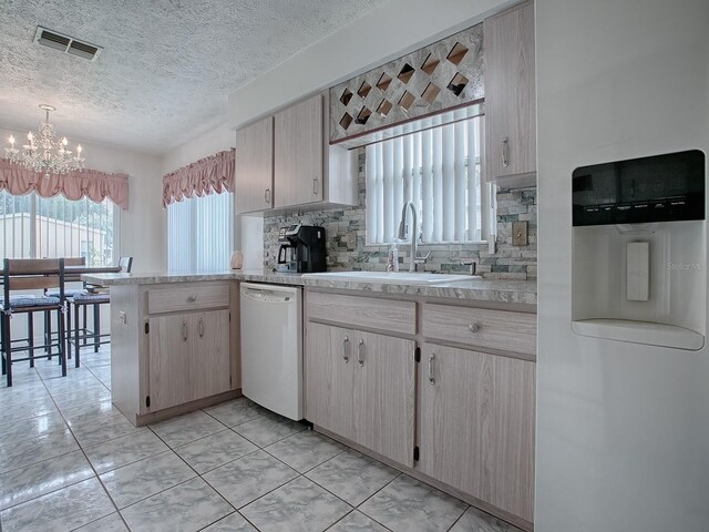 kitchen with a chandelier, sink, white appliances, backsplash, and light brown cabinets