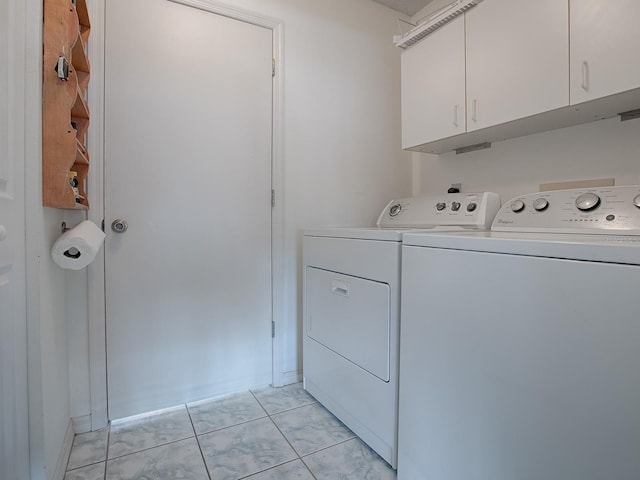 clothes washing area featuring cabinets, independent washer and dryer, and light tile patterned flooring