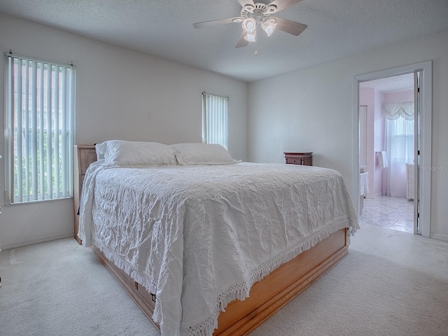 bedroom with light carpet, multiple windows, ceiling fan, and ensuite bathroom