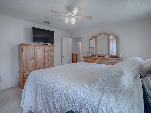 bedroom with a textured ceiling, light carpet, and ceiling fan