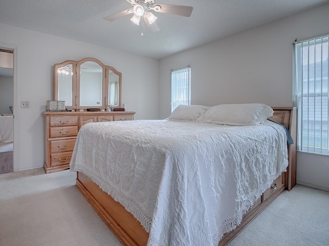 carpeted bedroom with ceiling fan, a textured ceiling, and multiple windows