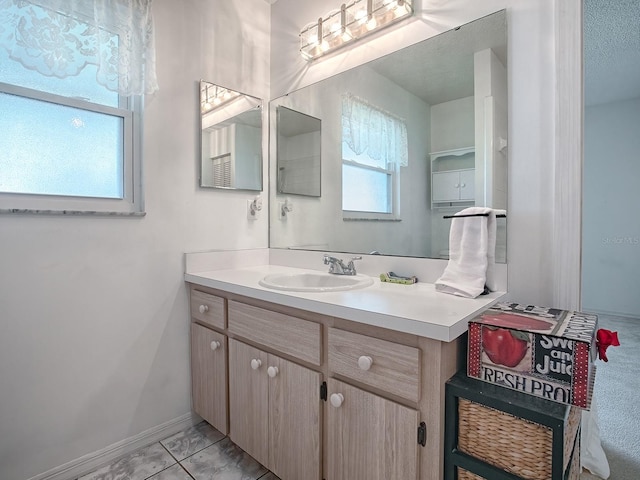 bathroom featuring a wealth of natural light, tile patterned floors, a textured ceiling, and vanity