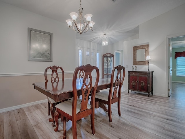 dining room with an inviting chandelier, a wealth of natural light, and light wood-type flooring