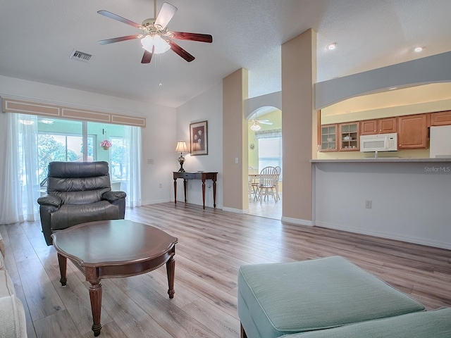 living room featuring a wealth of natural light, light hardwood / wood-style floors, ceiling fan, and vaulted ceiling