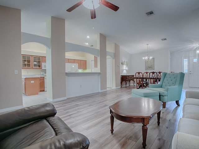 living room with ceiling fan with notable chandelier, vaulted ceiling, and light hardwood / wood-style flooring