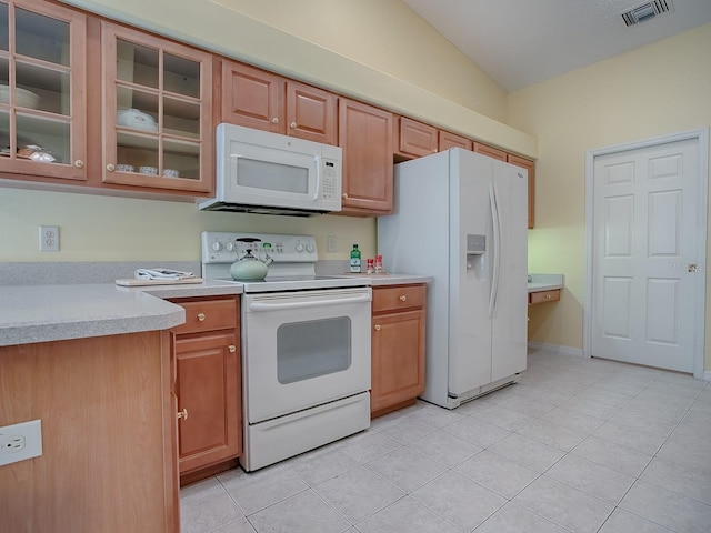 kitchen featuring white appliances, lofted ceiling, and light tile patterned floors