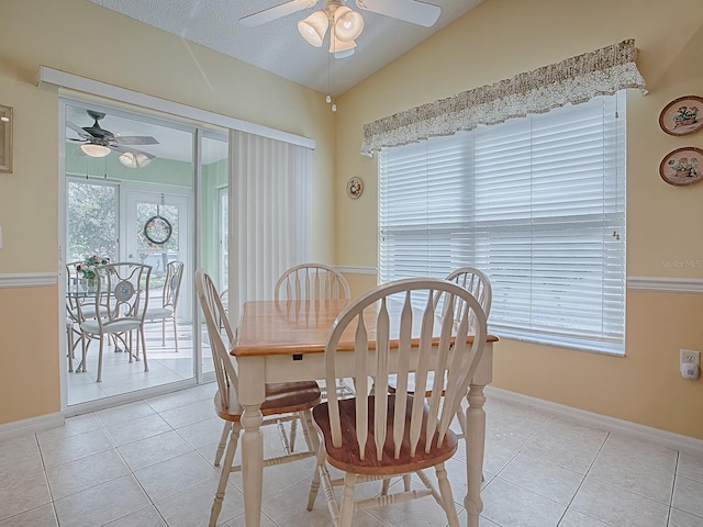 tiled dining space featuring vaulted ceiling, ceiling fan, and a textured ceiling