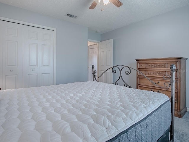 bedroom with ceiling fan, carpet floors, a closet, and a textured ceiling