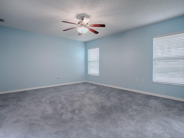 unfurnished room with dark carpet, ceiling fan, and a textured ceiling