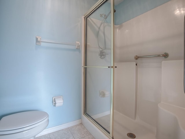 bathroom with a shower with door, toilet, and tile patterned floors