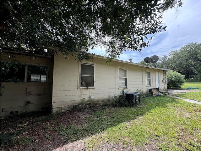 view of side of home featuring central AC unit and a yard