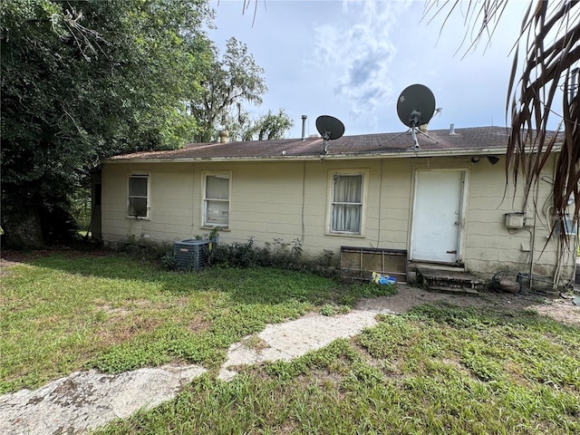 back of property with a lawn and central air condition unit