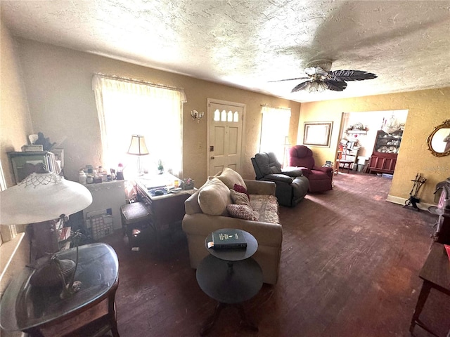 living room featuring ceiling fan, dark wood-type flooring, and a textured ceiling