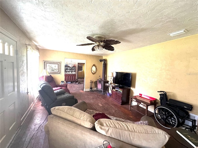 living room with a textured ceiling, dark hardwood / wood-style flooring, ceiling fan, and a wood stove