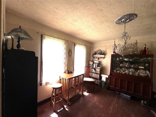 miscellaneous room featuring a textured ceiling, wood-type flooring, and an inviting chandelier