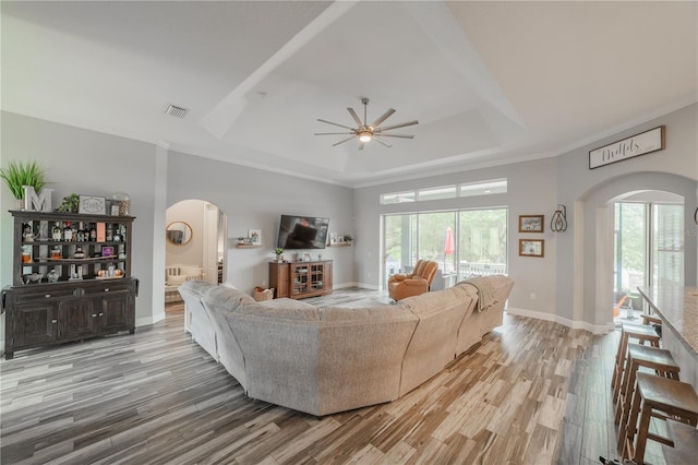 living room featuring crown molding, a raised ceiling, ceiling fan, and hardwood / wood-style flooring