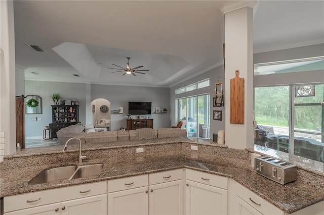 kitchen with white cabinetry, crown molding, ceiling fan, dark stone counters, and sink