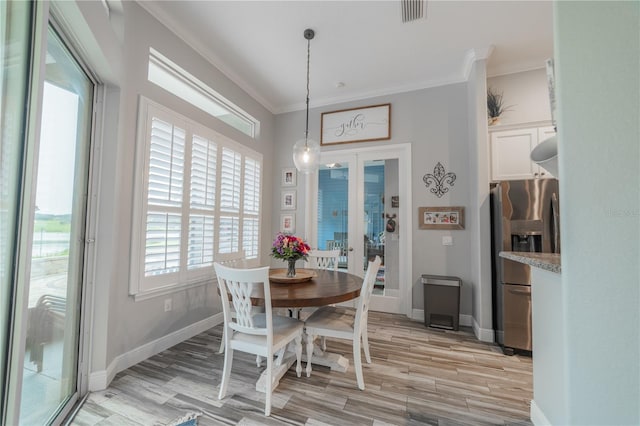 dining space with french doors, light hardwood / wood-style flooring, and crown molding