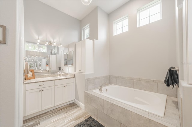 bathroom with tiled bath, hardwood / wood-style floors, and vanity