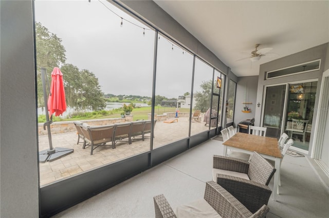 sunroom / solarium featuring ceiling fan and a water view