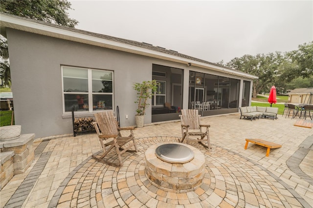 view of patio / terrace featuring a sunroom and an outdoor fire pit