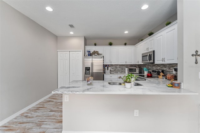 kitchen featuring stainless steel appliances, white cabinetry, kitchen peninsula, and a textured ceiling