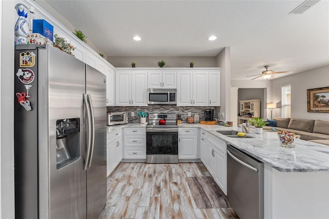 kitchen featuring white cabinets, stainless steel appliances, light wood-type flooring, ceiling fan, and sink